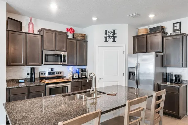a kitchen with stainless steel appliances granite countertop a refrigerator stove and microwave