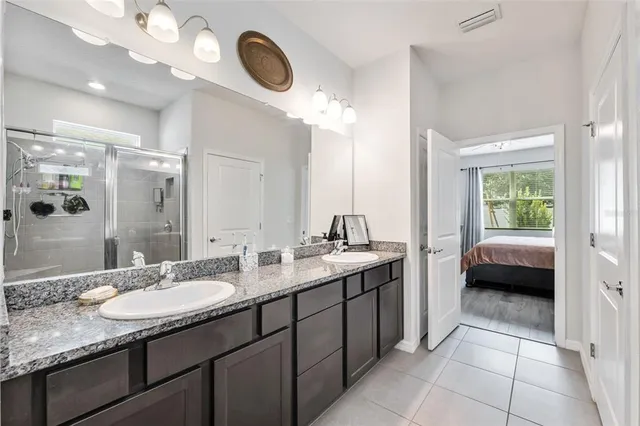 a en suite bathroom with a granite countertop sink a mirror and a shower