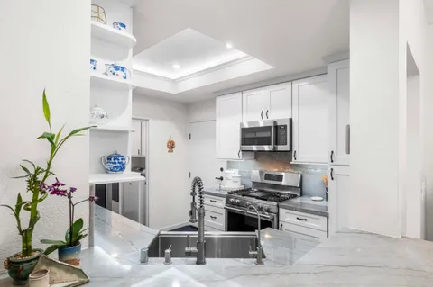 a kitchen with stainless steel appliances kitchen island granite countertop a refrigerator and a stove top oven