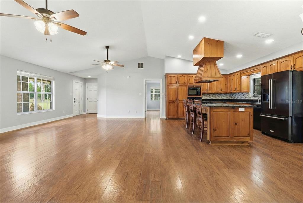 2331 D R Bryant Road Lakeland, FL 33810 - Photo 22 of 74 a open kitchen with stainless steel appliances granite countertop a refrigerator a stove a sink dishwasher and a stove with wooden floor