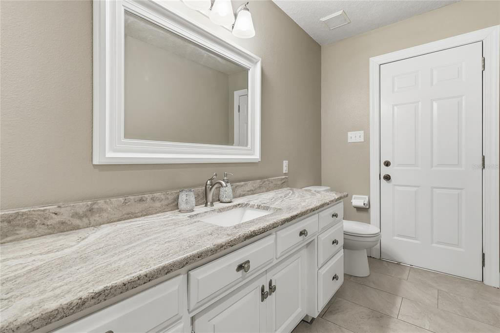 2331 D R Bryant Road Lakeland, FL 33810 - Photo 42 of 74 a bathroom with a granite countertop sink a toilet and a mirror