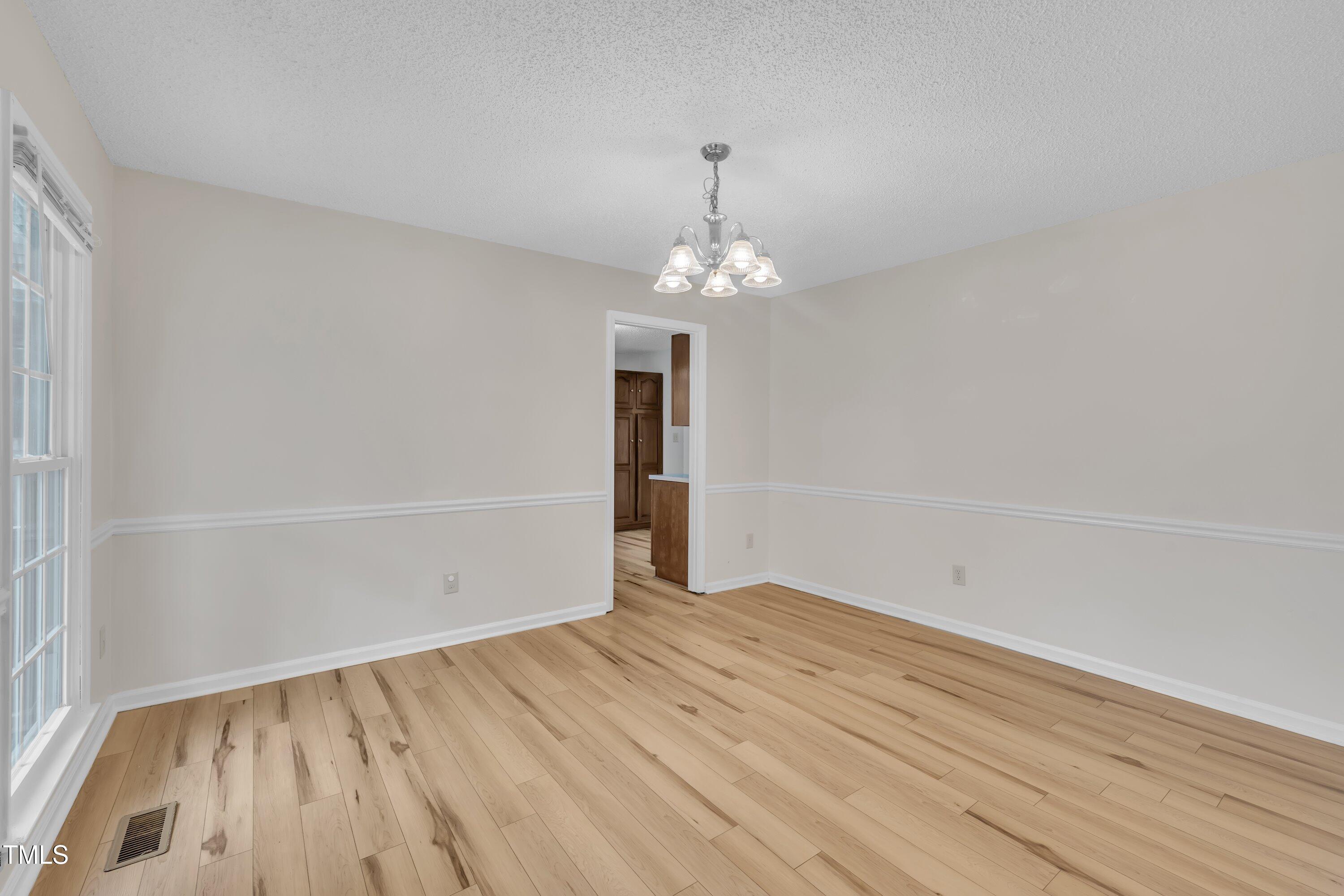 397 Meadow Road Kenly, NC 27542 - Photo 15 of 53 an empty room with wooden floor and chandelier