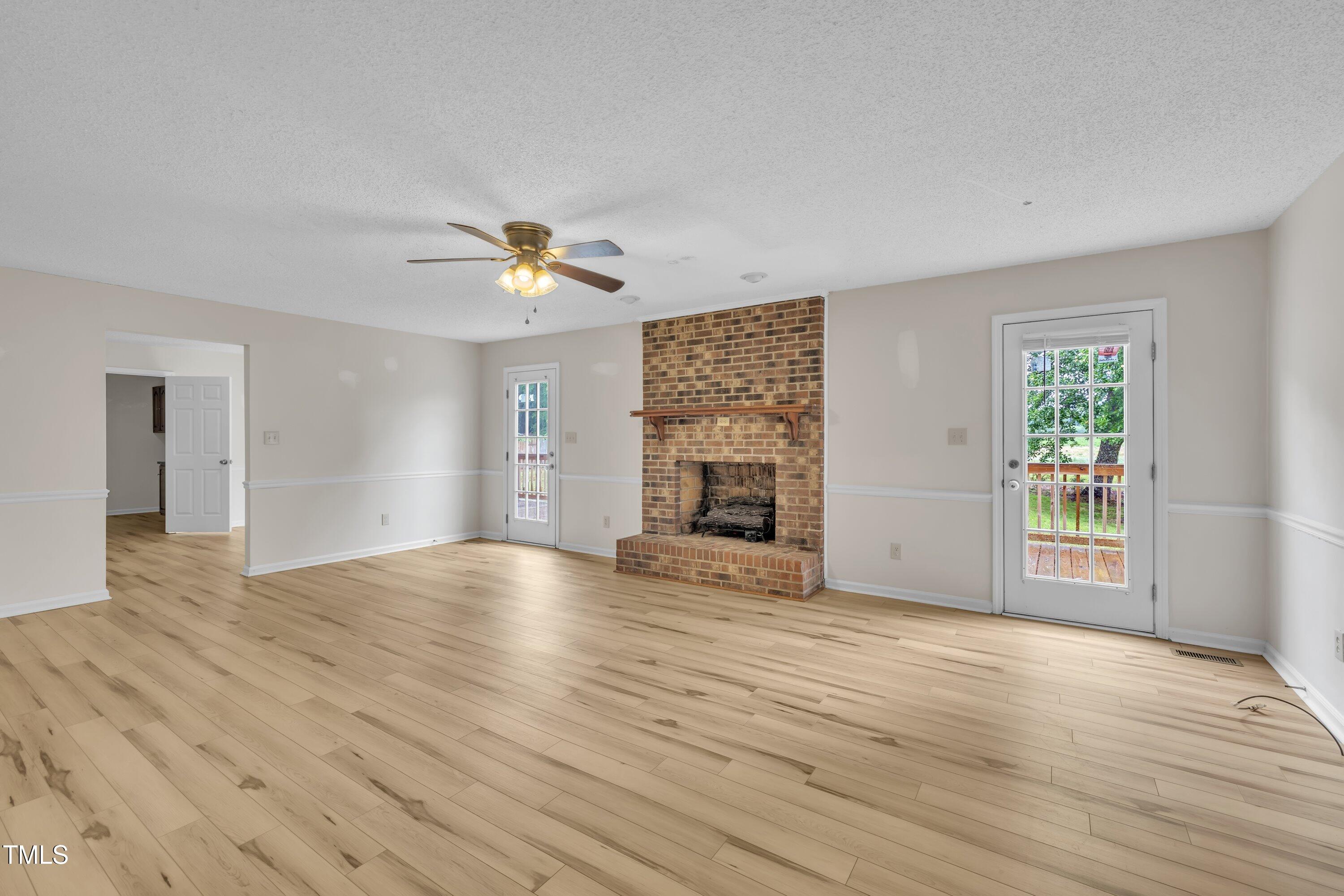 397 Meadow Road Kenly, NC 27542 - Photo 29 of 53 an empty room with wooden floor a fireplace and windows