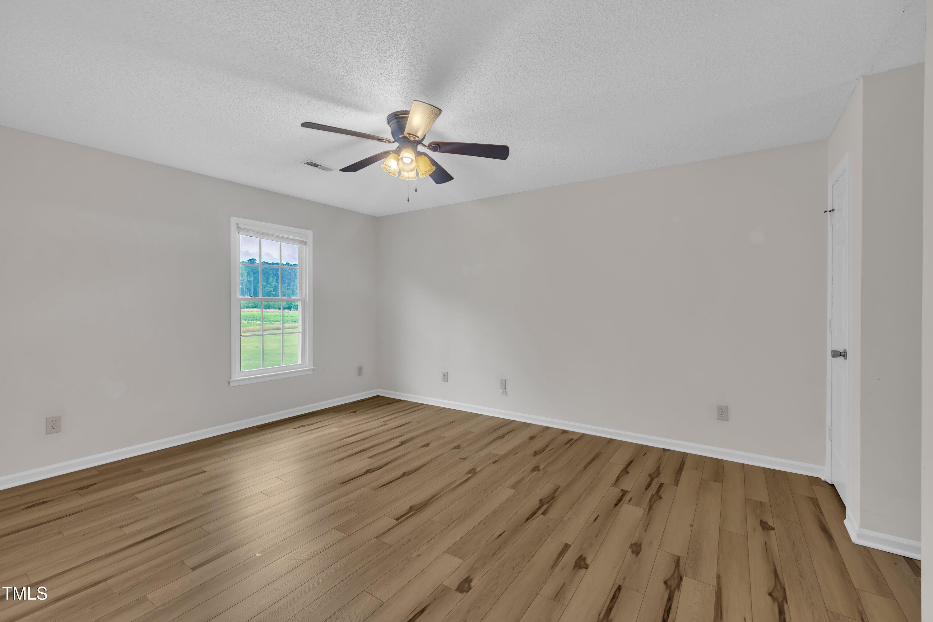 397 Meadow Road Kenly, NC 27542 - Photo 43 of 53 an empty room with wooden floor fan and windows