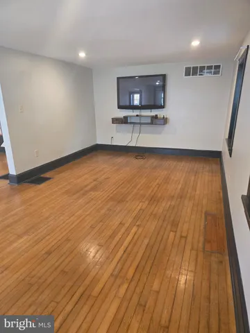 a view of kitchen and empty room with wooden floor