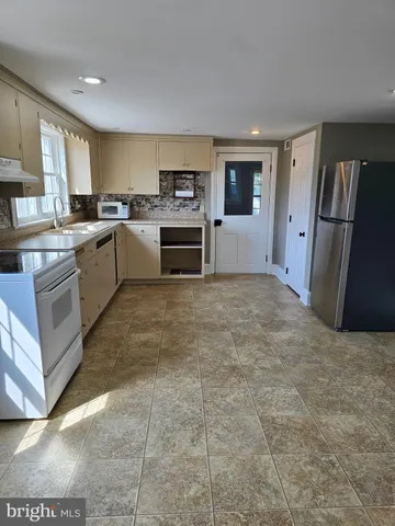 a large white kitchen with a stove a sink dishwasher and a refrigerator
