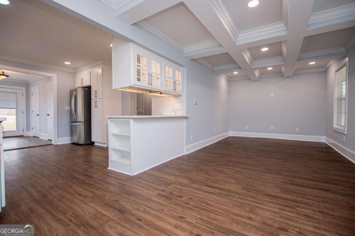 106 Mara Street Carrollton, GA 30117 - Photo 14 of 52 an empty room with wooden floor and kitchen view