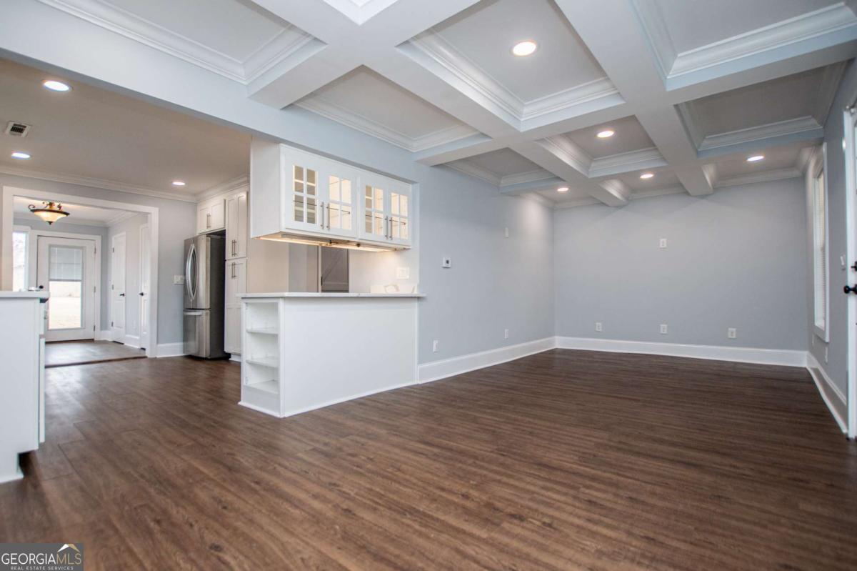 106 Mara Street Carrollton, GA 30117 - Photo 18 of 52 an empty room with wooden floor and kitchen view