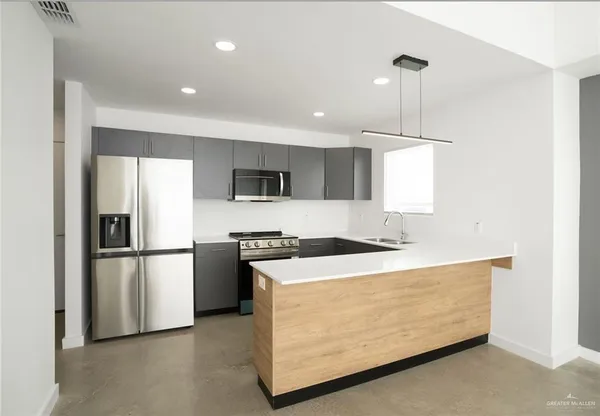 a kitchen with stainless steel appliances kitchen island a refrigerator sink and microwave