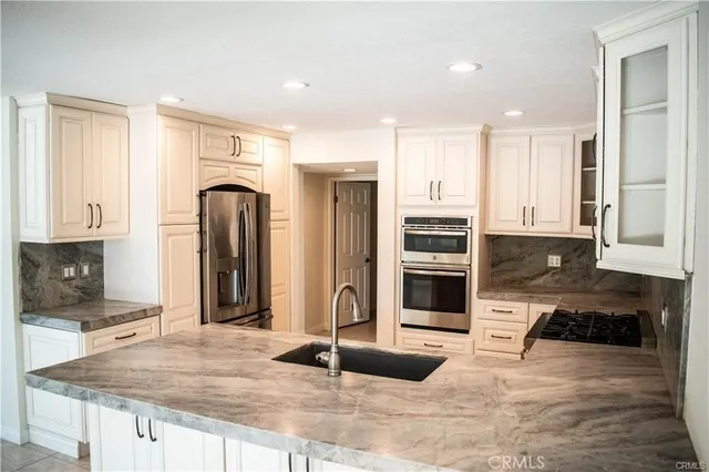 a kitchen with stainless steel appliances kitchen island granite countertop a stove and a refrigerator