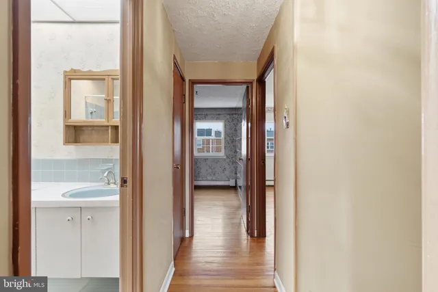 a view of a hallway with wooden floor and a bathroom