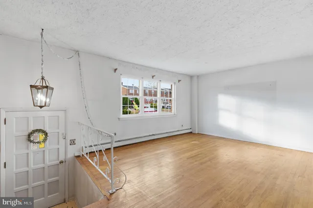 a view of an empty room with window and wooden floor