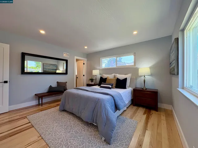 a bedroom with bed mirror and window