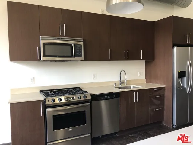 a kitchen with stainless steel appliances a sink a stove a microwave and wooden cabinets