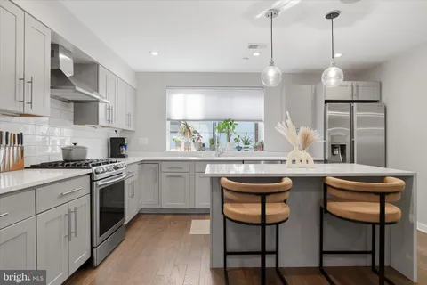 a kitchen with stainless steel appliances granite countertop a table chairs refrigerator and microwave