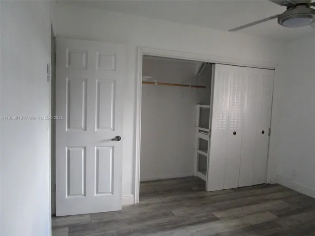 an empty room with wooden floor and closet area