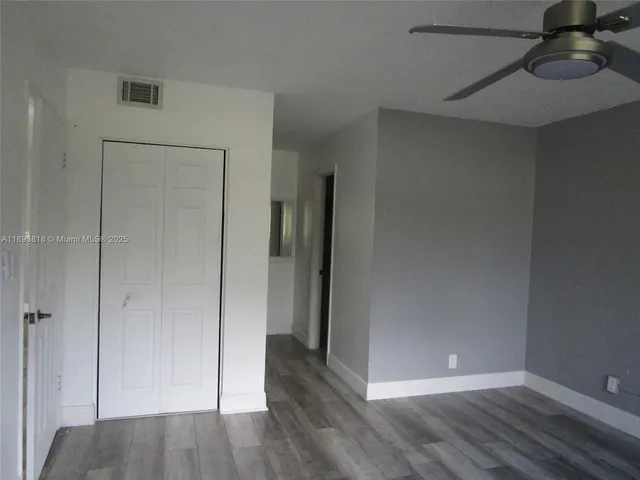 a view of an empty room with closet and wooden floor