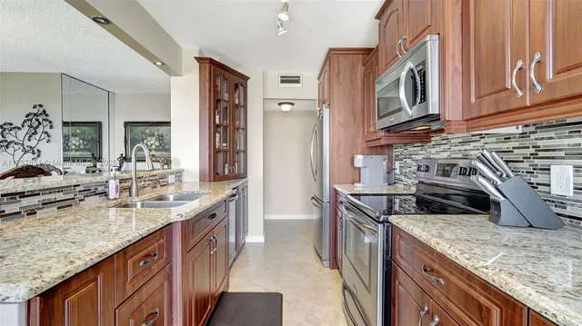 a kitchen with kitchen island granite countertop a sink stove and cabinets