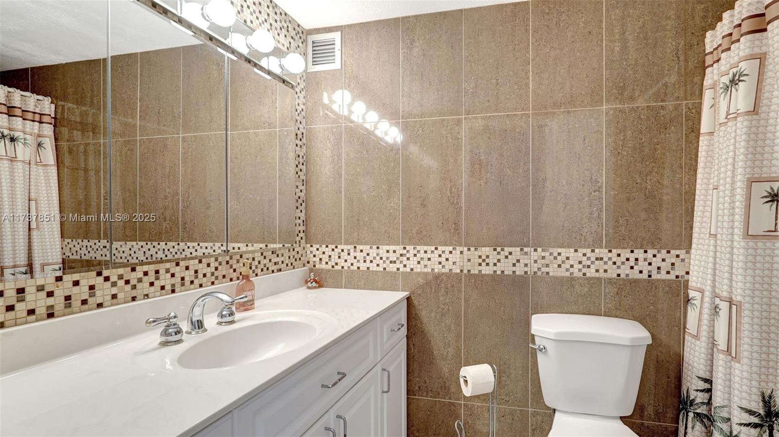 322 Buchanan Street, Unit 907 Hollywood, FL 33019 - Photo 30 of 45 a bathroom with a sink a toilet and a mirror