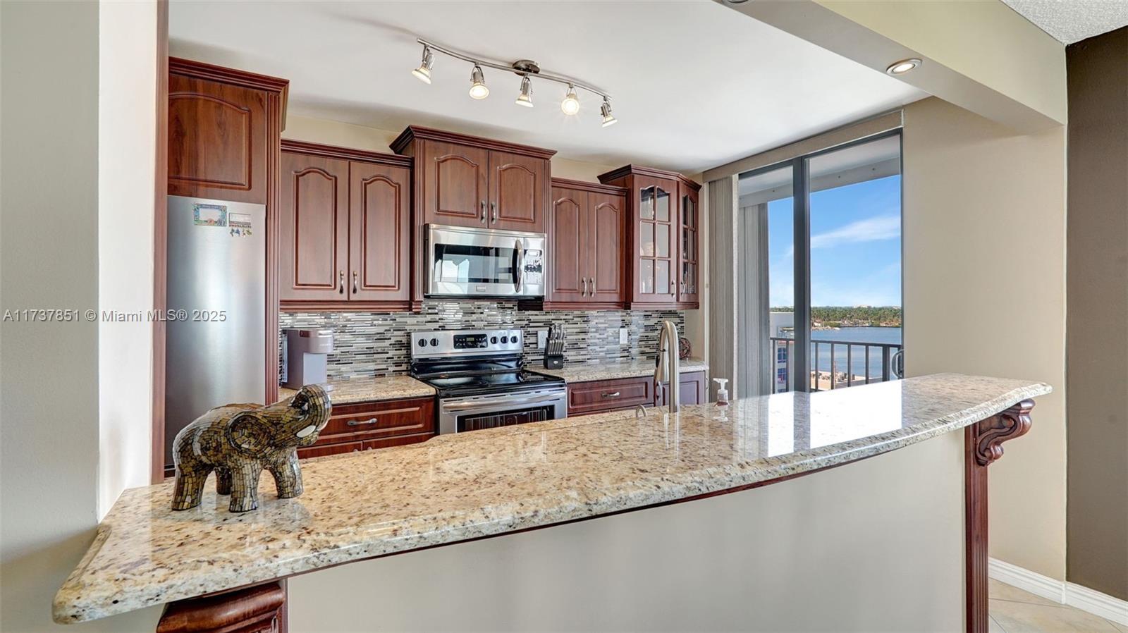 322 Buchanan Street, Unit 907 Hollywood, FL 33019 - Photo 6 of 45 a kitchen with stainless steel appliances granite countertop a sink a stove and a microwave