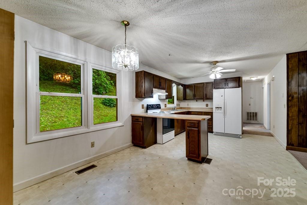 302 Mitchell Road Sylva, NC 28779 - Photo 10 of 48 a kitchen with stainless steel appliances granite countertop a refrigerator a oven a sink with a dining table and chairs