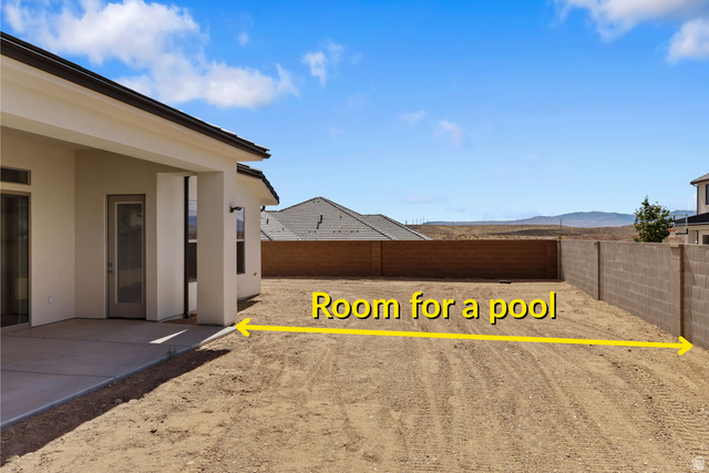 2955 East Rimrunner Drive St. George, UT 84790 - Photo 29 of 35 Expansive rear yard featuring an attached covered patio, concrete block perimeter fencing, and a vast undeveloped space