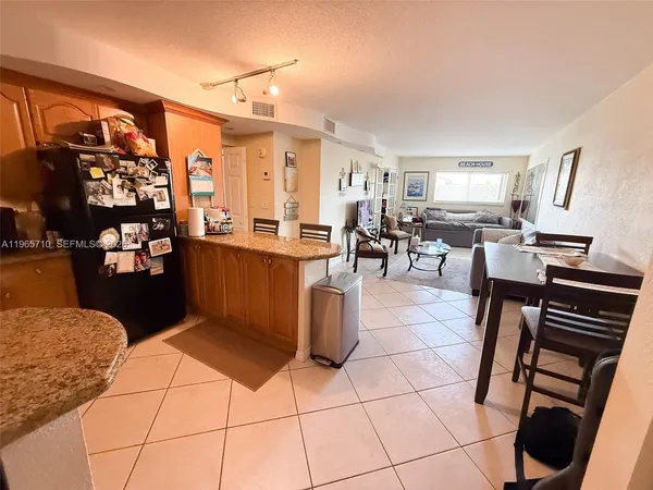 a living room with couches a flat tv screen and kitchen view