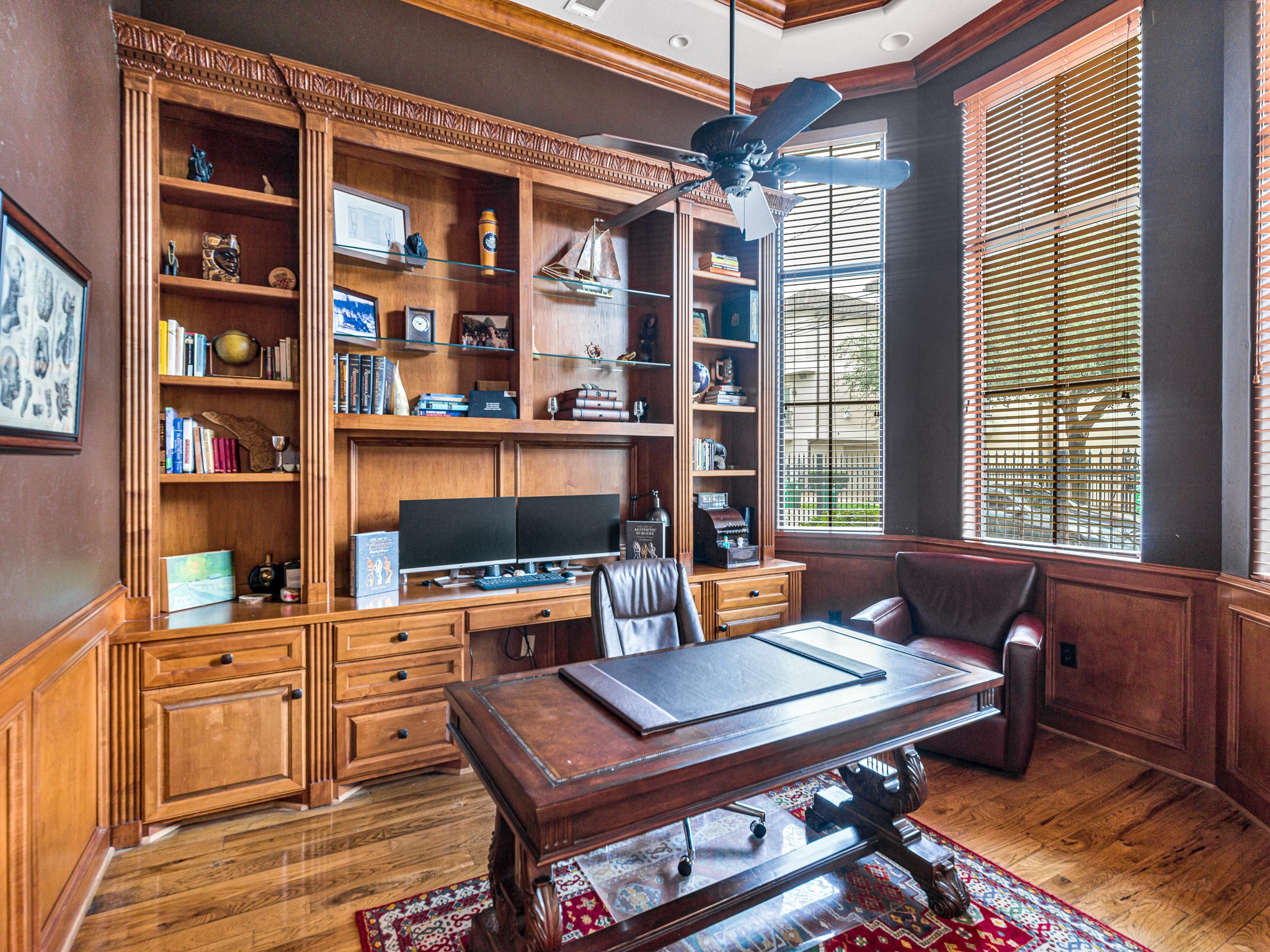 4614 Inker Street Houston, TX 77007 - Photo 7 of 36 Home office with rich wood built-in shelves. The room features hardwood floors and large windows with blinds that let in natural light, creating a warm and inviting workspace.