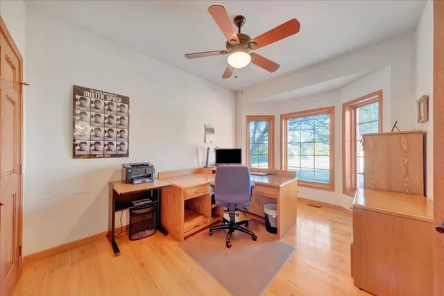 a workspace with wooden floor and a chandelier fan