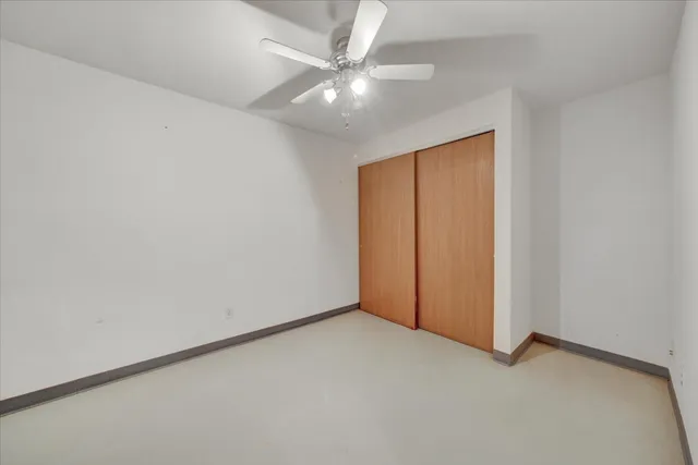 an empty room with a ceiling fan and a window