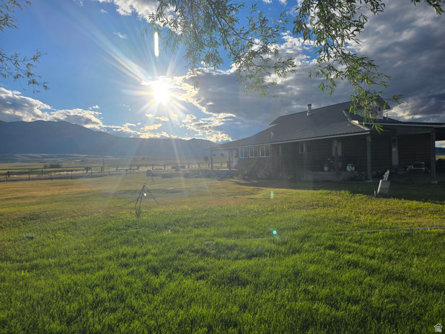 34200 Coulam Road Swan Lake, ID 83281 - Photo 20 of 24 Expansive green lawn with a dark-sided ranch-style home featuring a covered porch and metal roof