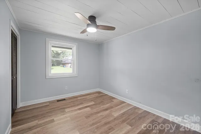 an empty room with a window and ceiling fan
