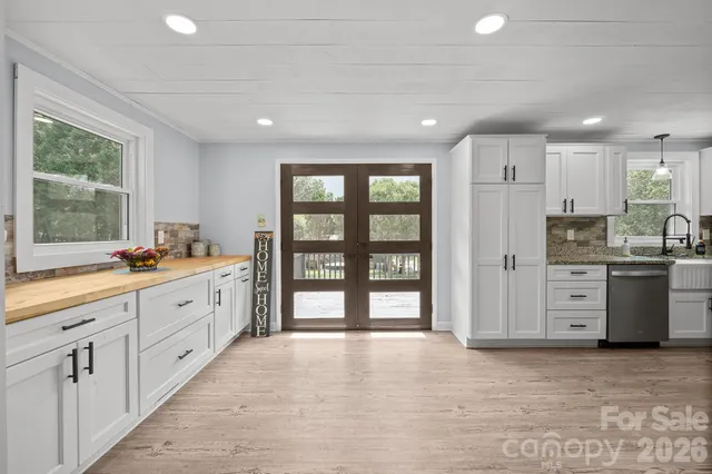 a large kitchen with kitchen island a large window a sink stainless steel appliances and cabinets