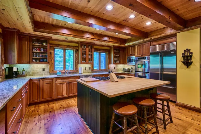 a kitchen with stainless steel appliances granite countertop a sink a stove and a wooden table