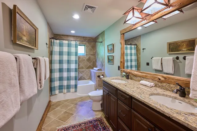 a bathroom with a granite countertop double vanity sink and a mirror