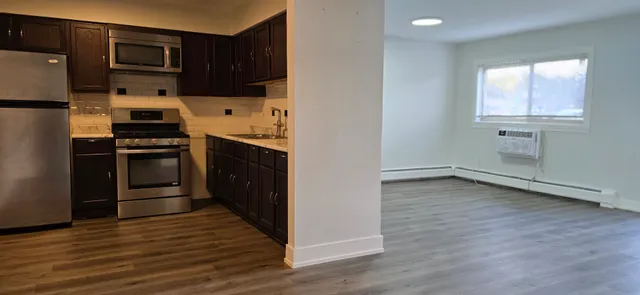 a kitchen with a refrigerator stove and wooden floor