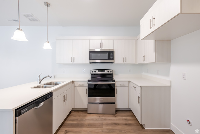 4664 South 680th West, Unit S303 Mapleton, UT 84664 - Photo 13 of 18 Modern kitchen featuring white cabinetry, light countertops, wood-finish flooring, stainless steel appliances, and pendant lighting