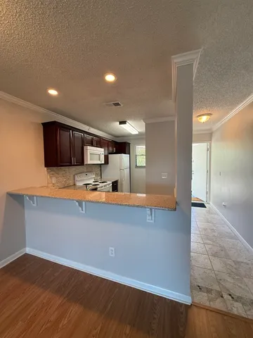 a large kitchen with stainless steel appliances a large counter top a stove and a refrigerator