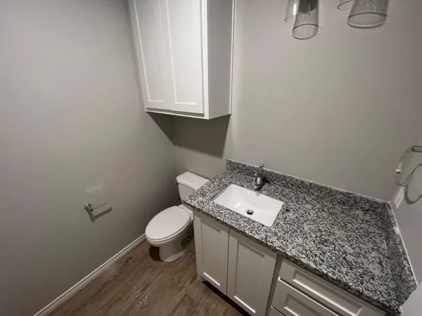 a bathroom with a granite countertop sink and a toilet