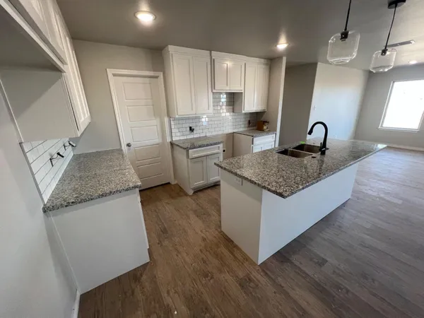 a kitchen with granite countertop a sink stove and refrigerator