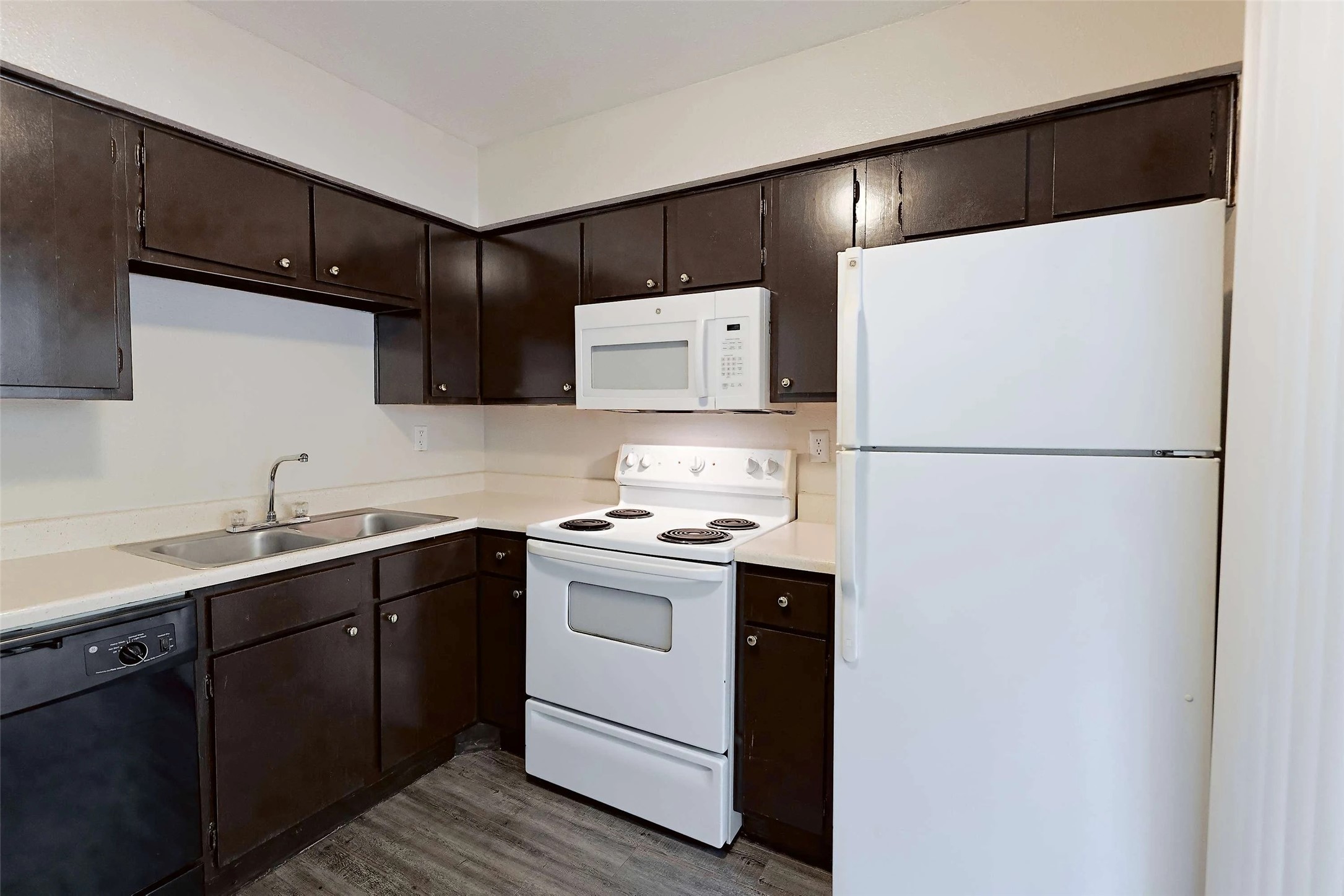 2809 West William Cannon Drive, Unit I101 Austin, TX 78745 - Photo 4 of 29 Kitchen with white appliances, dark brown cabinetry, light countertops, and dark wood finished floors