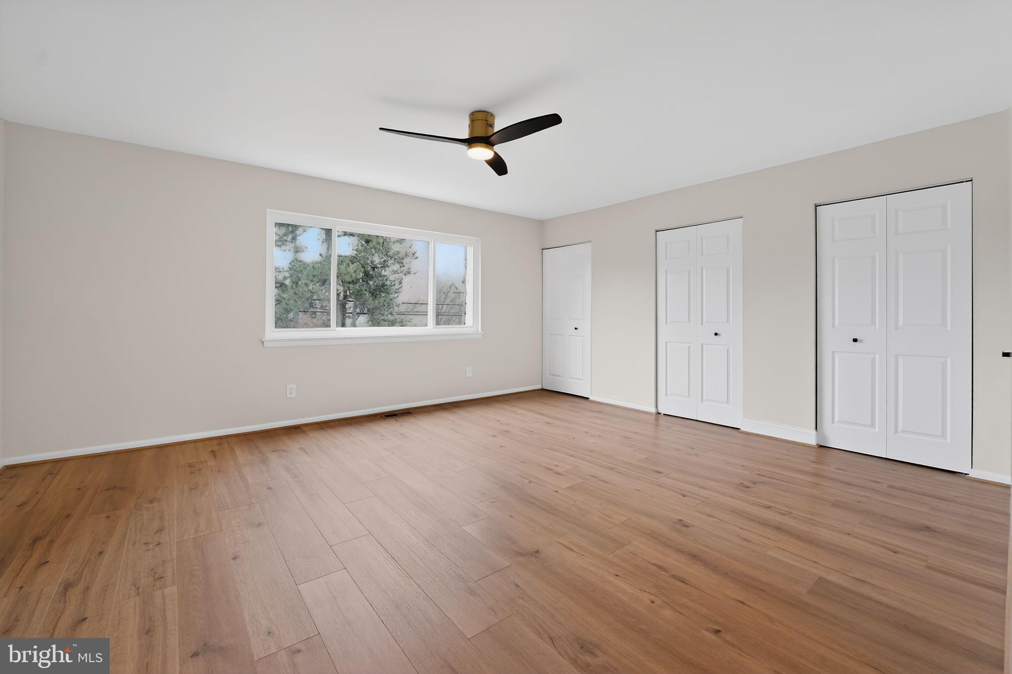 7344 Park Heights Avenue Baltimore, MD 21208 - Photo 20 of 33 an empty room with wooden floor a ceiling fan and windows