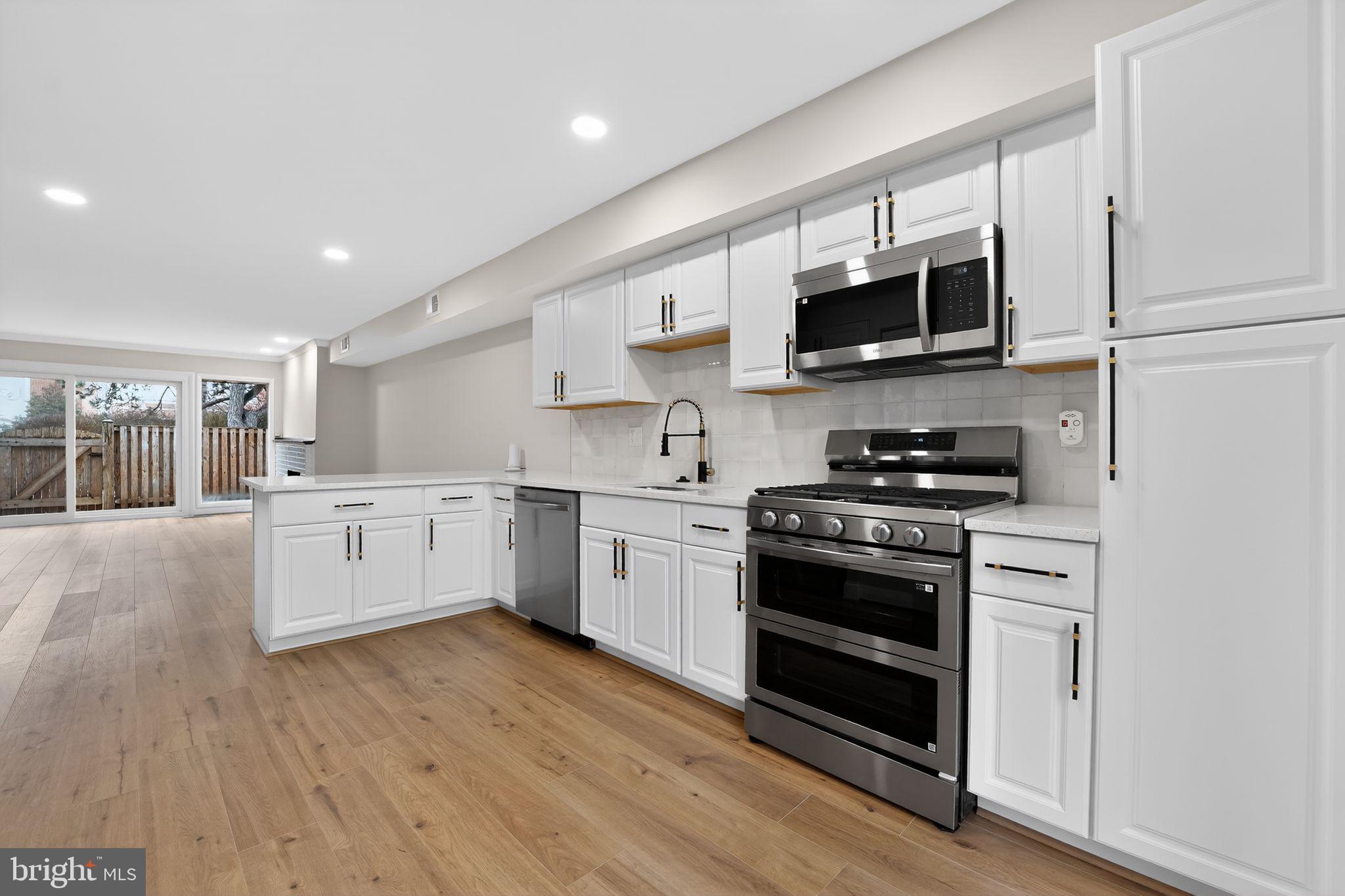 7344 Park Heights Avenue Baltimore, MD 21208 - Photo 2 of 33 a kitchen with stainless steel appliances white cabinets and wooden floors