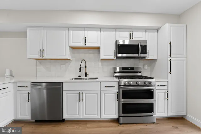 a kitchen with white cabinets and stainless steel appliances