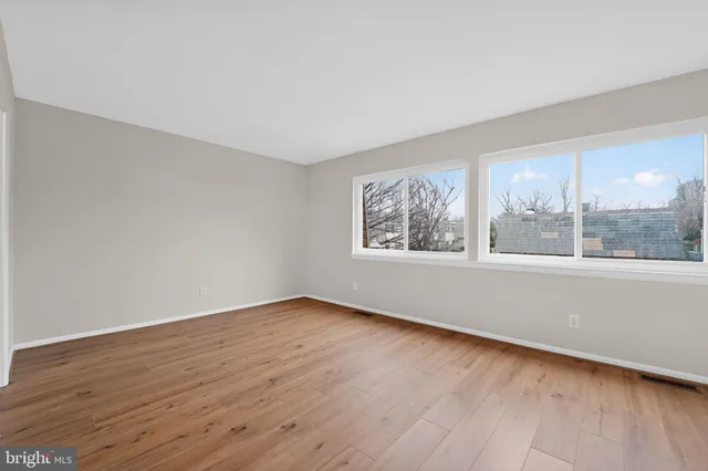 an empty room with wooden floor and windows
