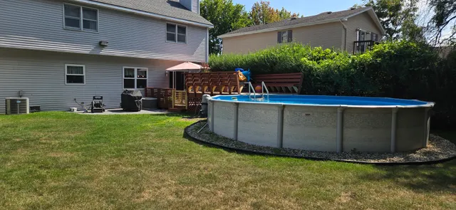 a view of a backyard with table and chairs potted plants and large tree