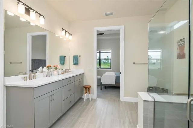 a en suite bathroom with a double vanity sink a mirror and shower