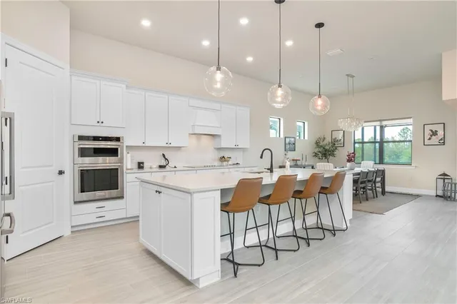 a large kitchen with kitchen island a island a stove a cabinets a sink a dining table and chairs