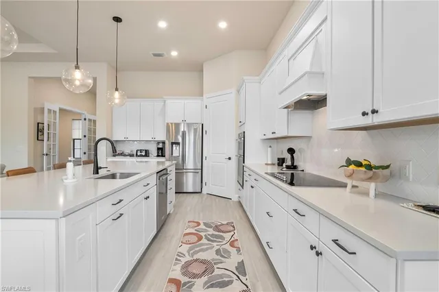 a kitchen with white cabinets sink and stainless steel appliances