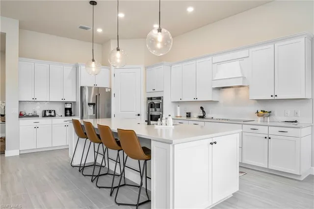a kitchen with stainless steel appliances kitchen island a table chairs refrigerator sink and cabinets